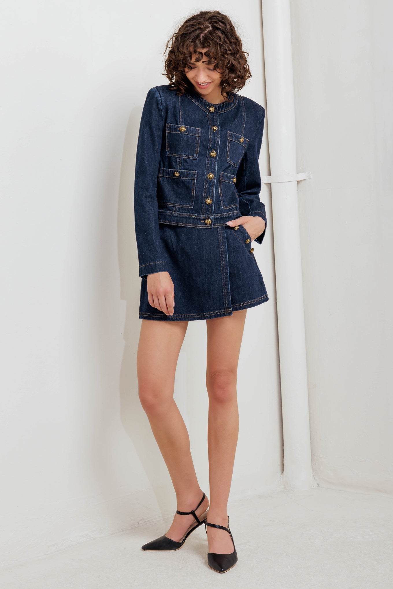 Woman wearing a denim dress and jacket against a white background