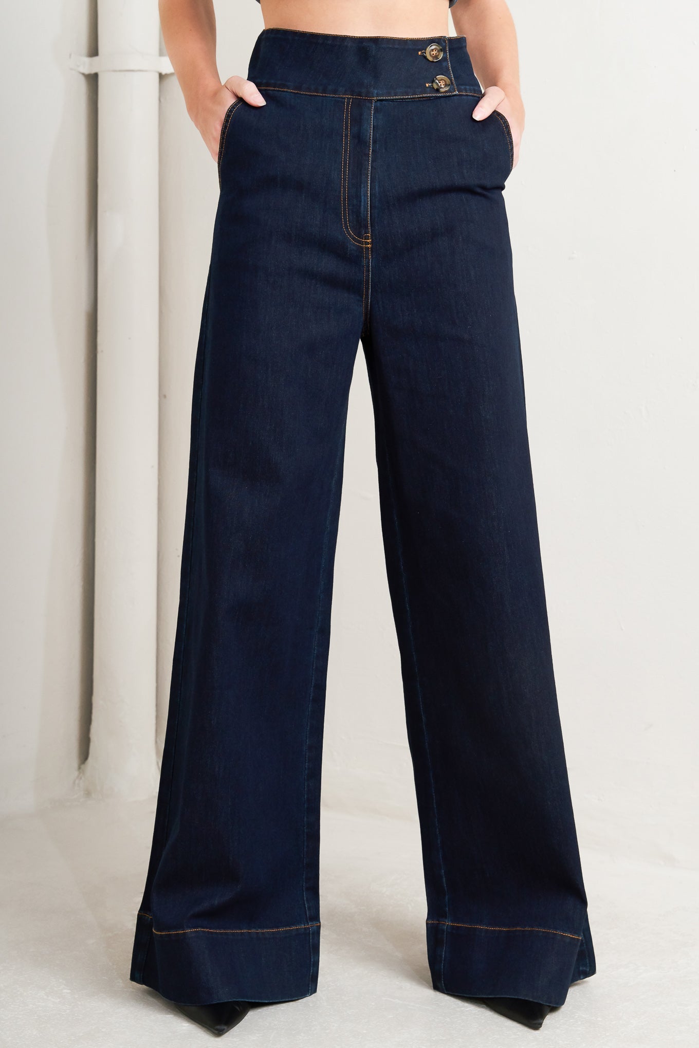 Dark blue wide-leg jeans worn by a person on a light background