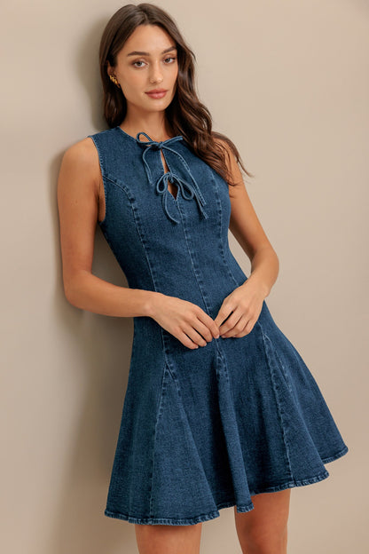 Woman wearing a blue denim dress against a beige background