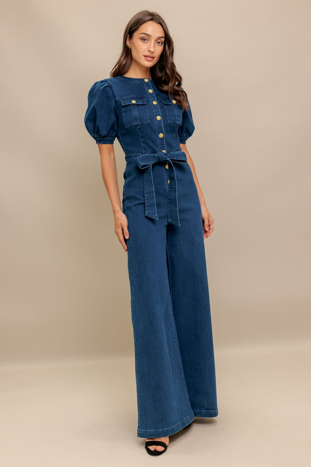 Woman wearing a denim outfit with puff sleeves on a beige background