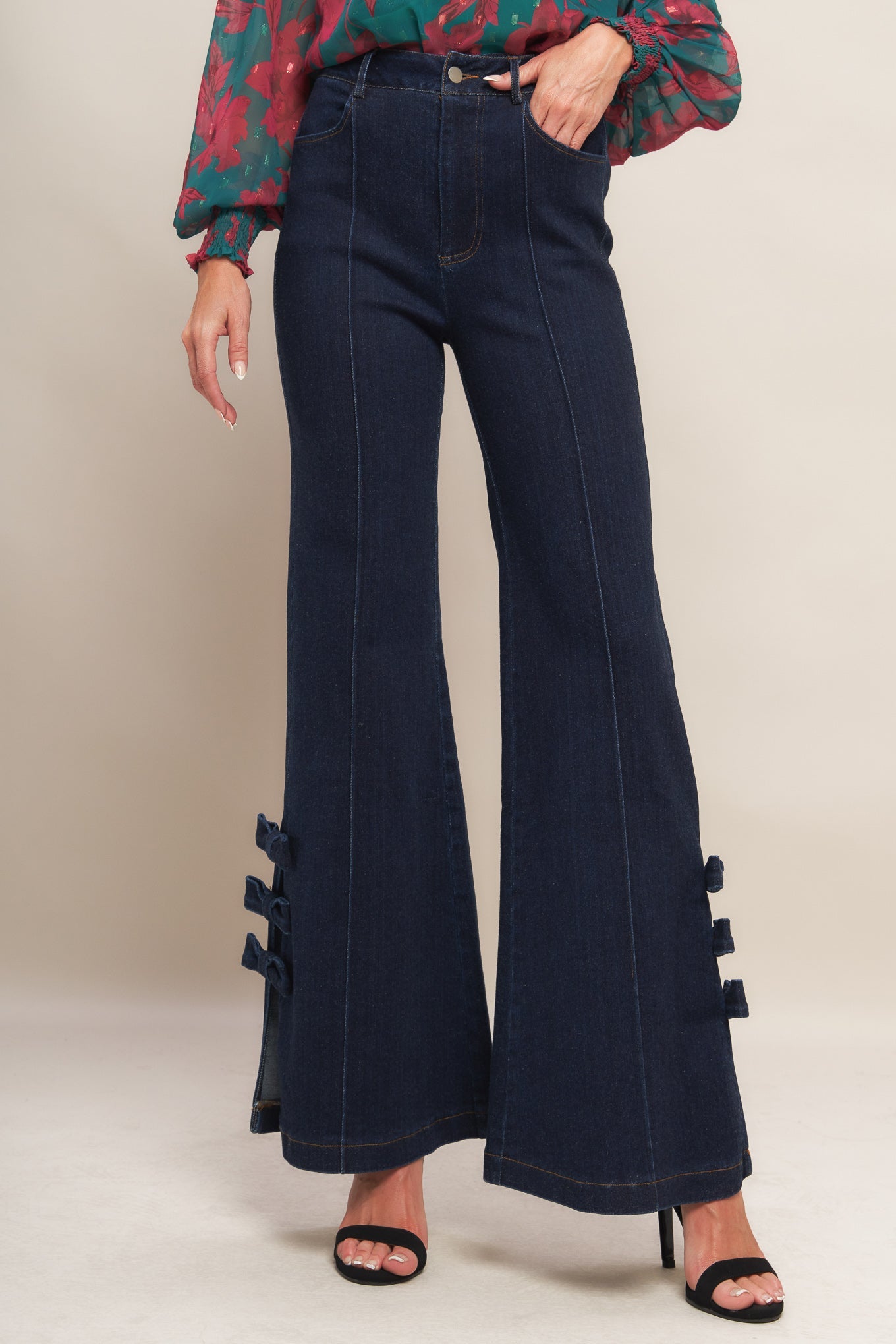 Navy blue flared jeans with decorative bows on a plain background