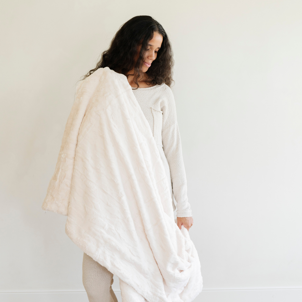 Woman wearing a white blanket against a plain background
