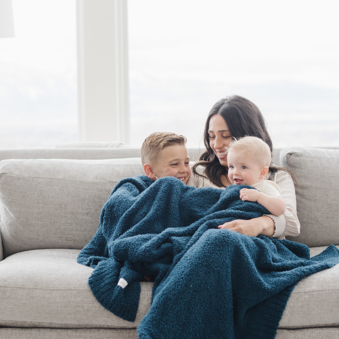 Woman and two children on a couch with a blue blanket