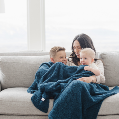 Woman and two children on a couch with a blue blanket